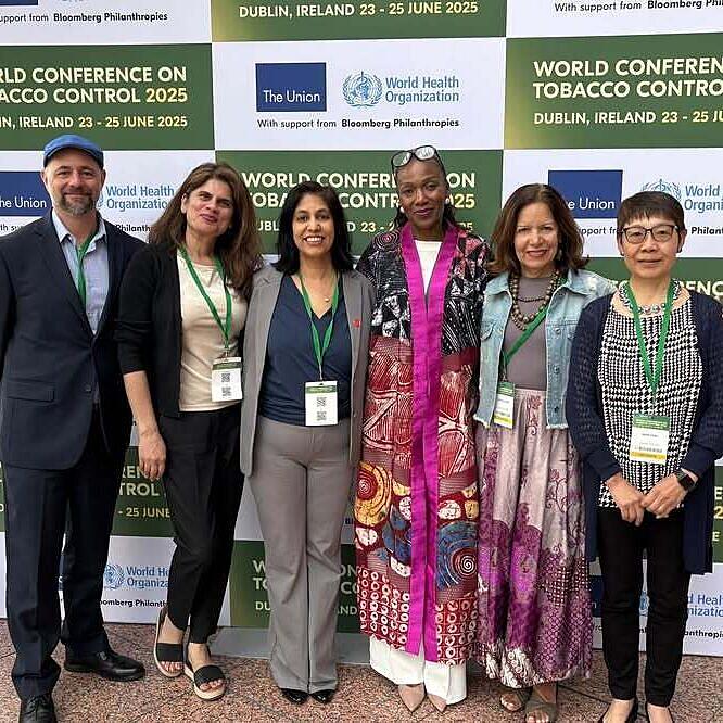 Staff pose in front of signage at a conference.