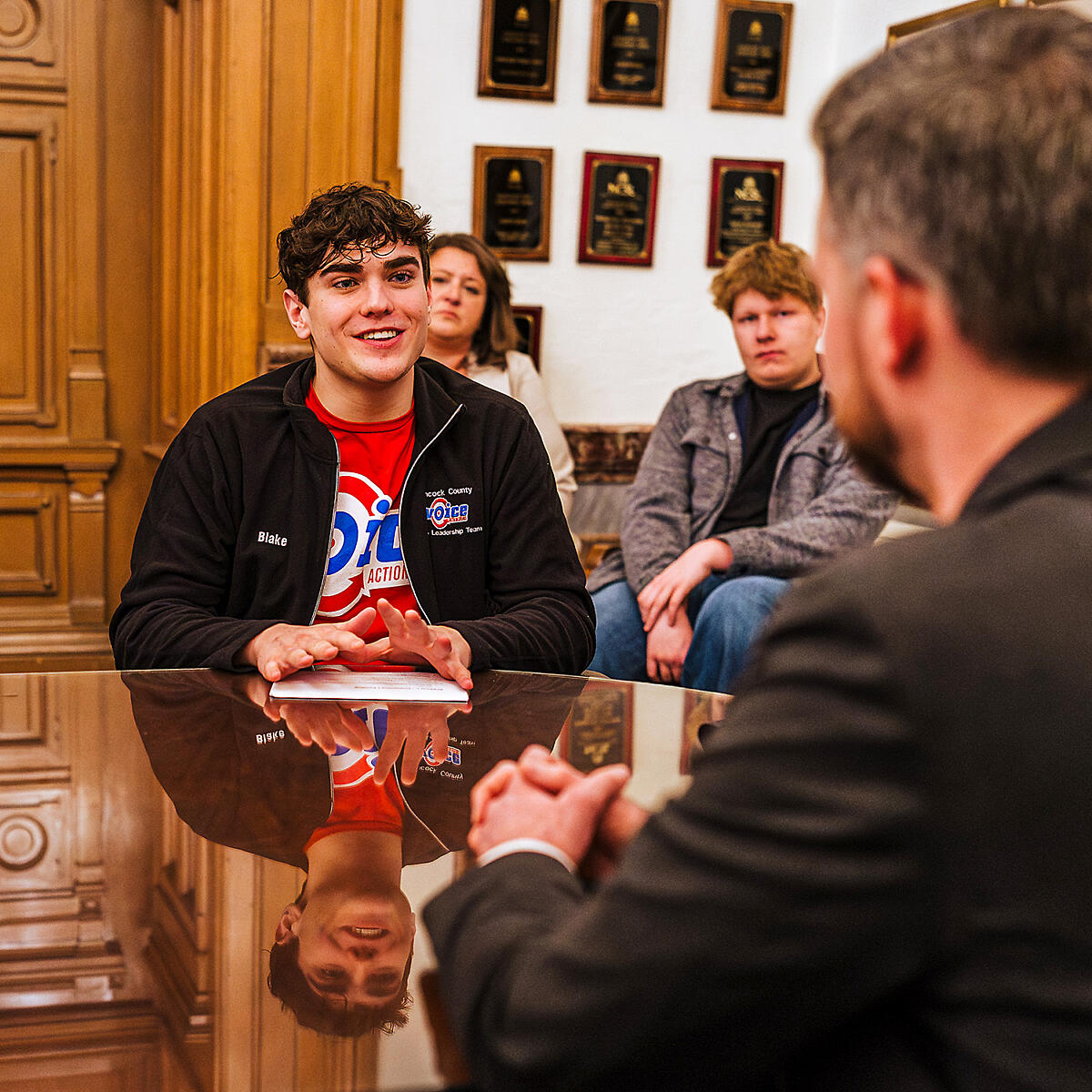 A male youth activist sits across a table from a legislator.